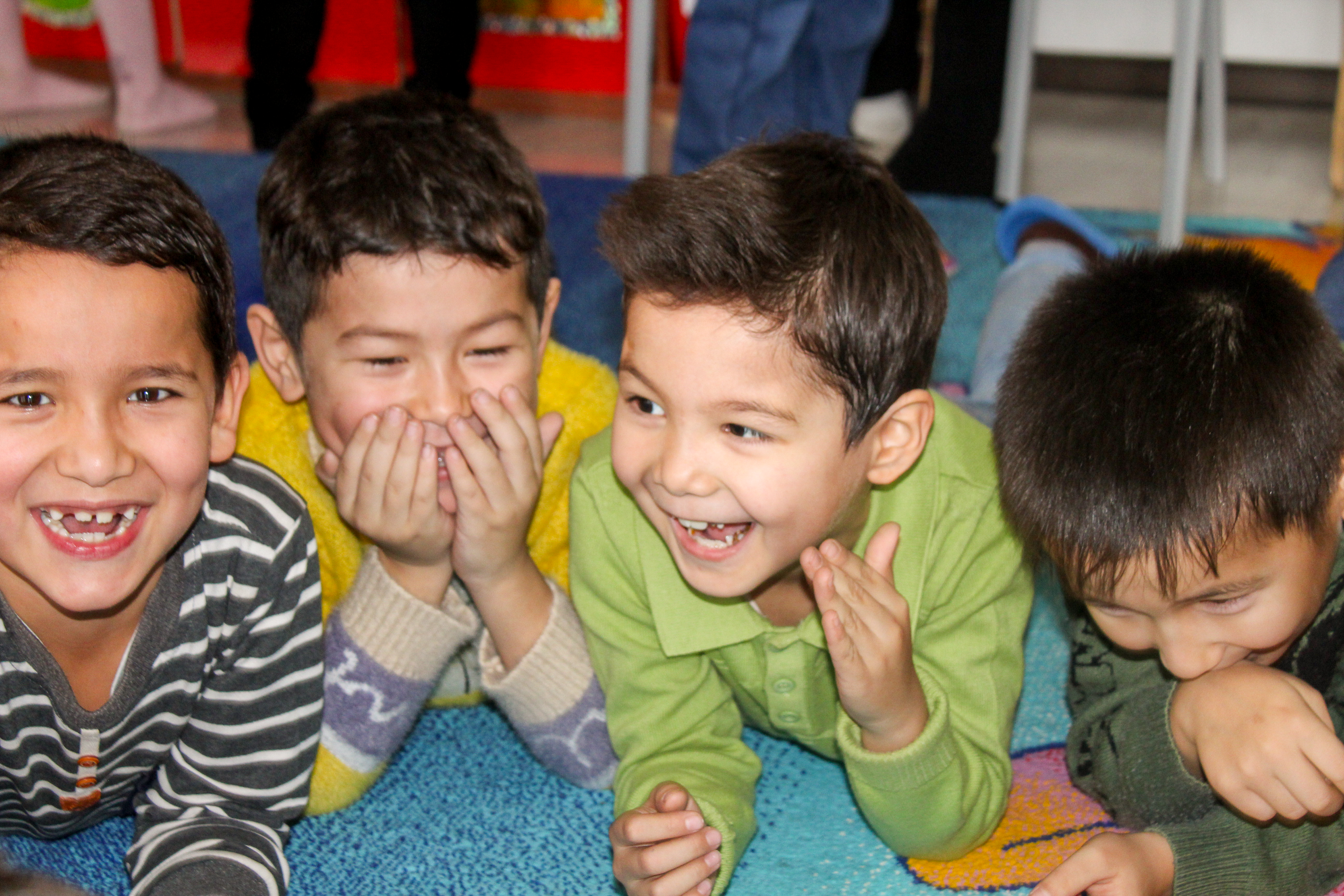 Four young children lying on a floor and laughing