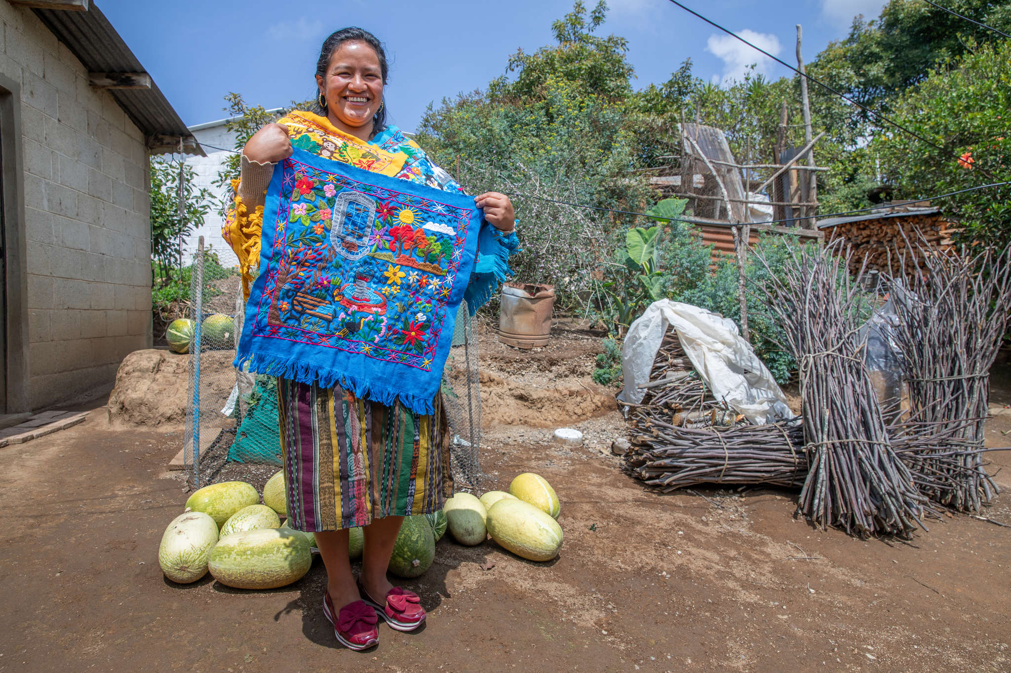 A person holding a brightly colored piece of clothing they made by hand.