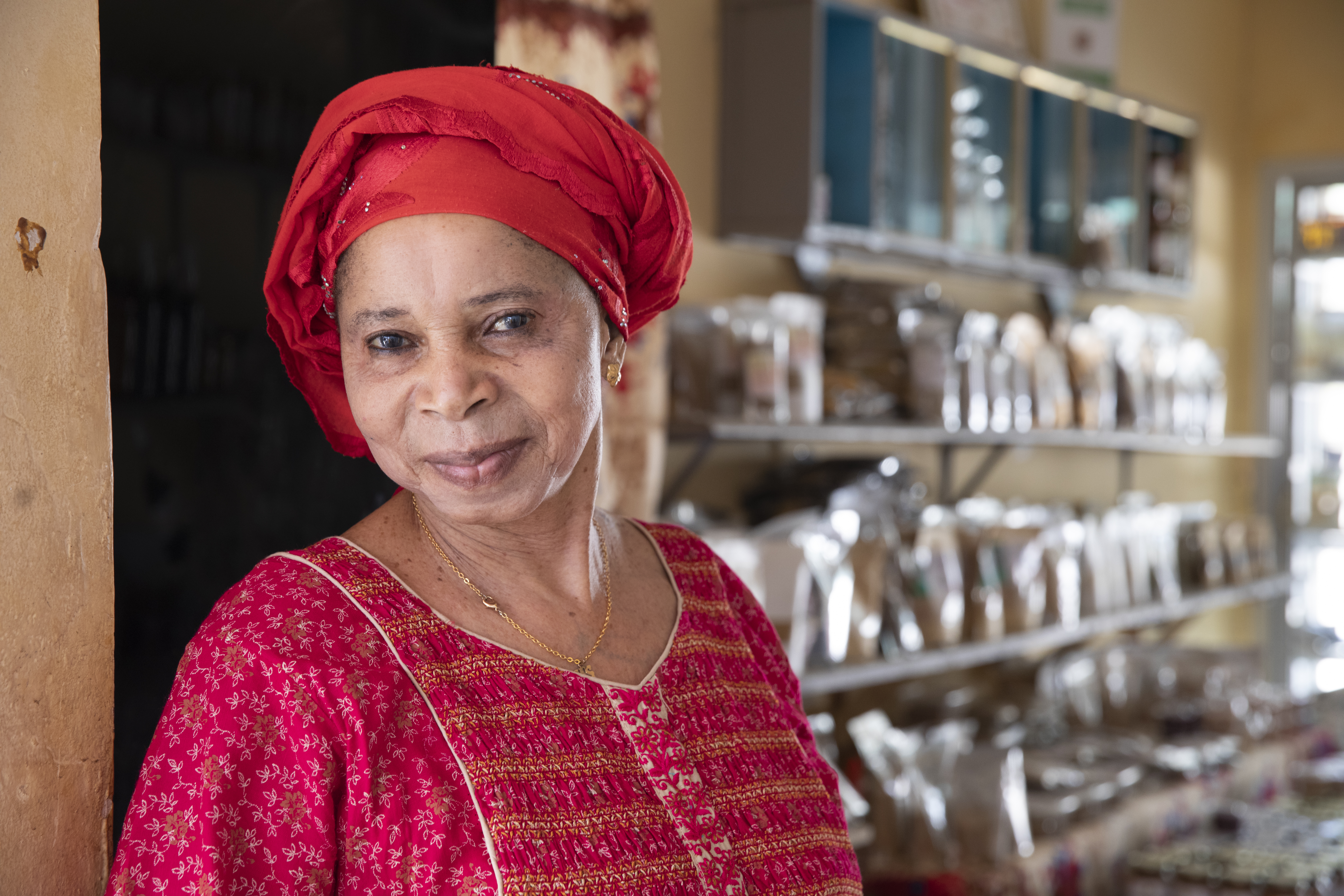 Senegalese female entrepreneur stands in her business smiling.