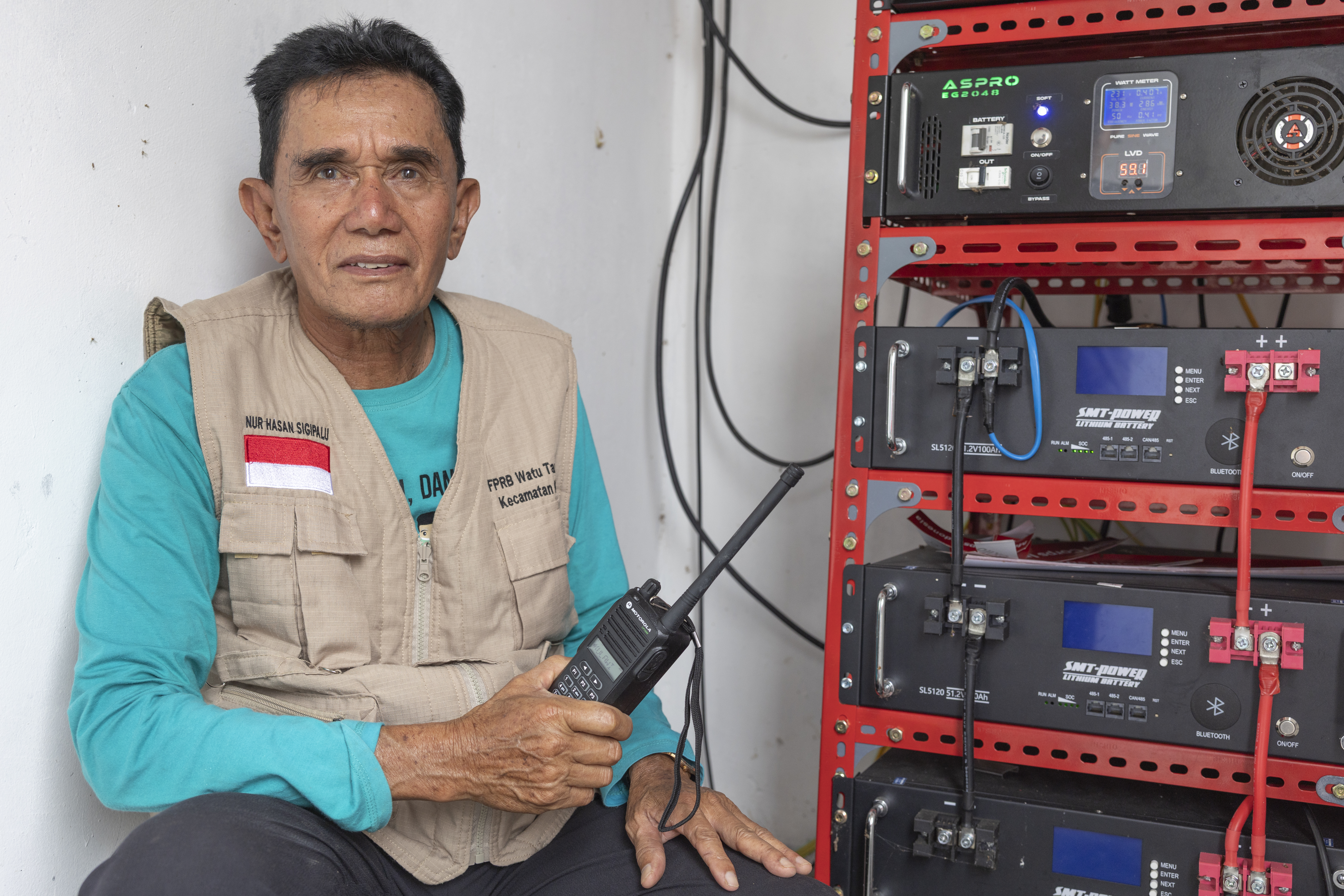 Indonesian man with hand radio and broadcasting equipment intended for use during emergency moments.