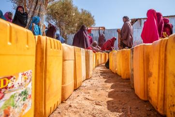 Displaced women line up to fill their jerrycans