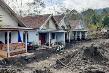 Houses in a village damaged after a nearby volcano erupted.