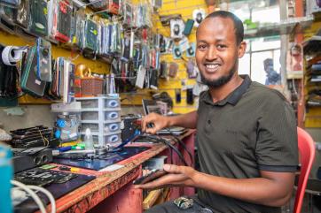 A person repairing a mobile device at their shop.