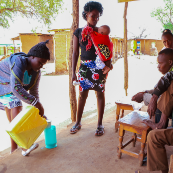 A group of people watch a person pour milk into a pitcher.