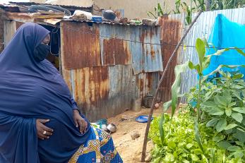 Hadiza sits in front of her small at-home garden she grew from seeds.