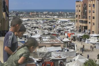 Palestinian children on a balcony overlooking a displaced peoples encampment. 