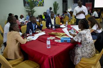 Ugandan professionals sit at table discussing energy access and last-mile distribution.