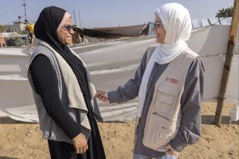 Two palestinian woman, mercy corps employees, greet each other and chat.