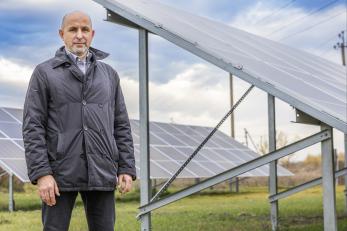 Ukrainian man stands among a solar panel array.