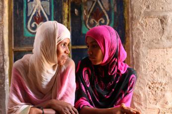 A mother and child sit together and look at each other.