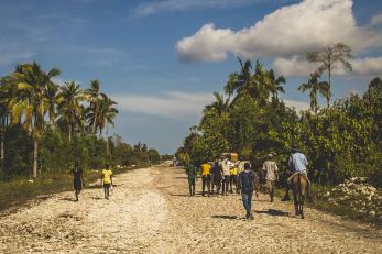 People walking along an unpaved road in Haiti.