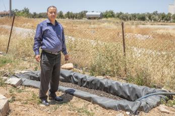 A person standing next to next to the greywater system at their home.