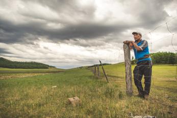 Mongolian farmer looking over a landscape view of agricultural land.