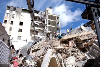 Venezuelan emergency crews work through rubble of building.