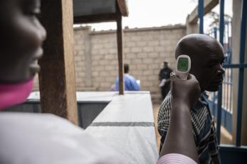 A health worker takes the temperature of an individual.