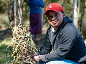 man in Guatemala wearing a red Mercy Corps hat in a field