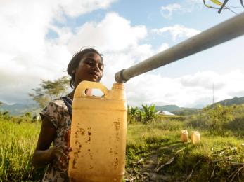 A person in Timor Leste filling up a jerrycan with water from a pipe.