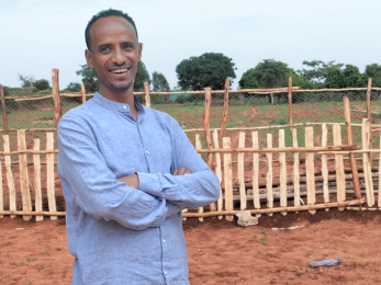 man standing outside in front of wooden fence
