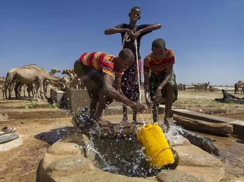 Three young people work together to haul up water in ethiopia.
