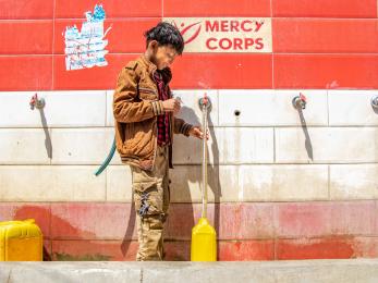 A young person fills a jerry can at a water point which was built by mercy corps. 