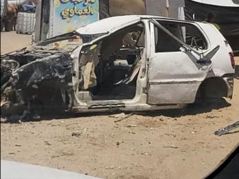 Destroyed automobile in the middle of a street in gaza.