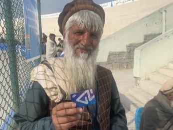 Hesabpay user stands outside fenced area showing payment card.