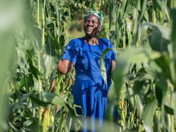 Smallholder farmer Rose Siama standing among crops.