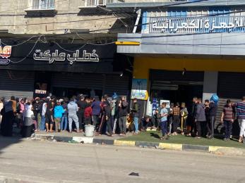 People standing in line outside of a bakery in rafah