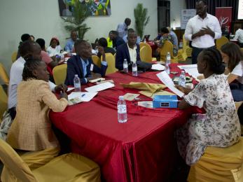 Ugandan professionals sit at table discussing energy access and last-mile distribution.