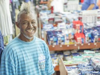 Puerto rican man stands amidst commercial stalls, smiling.